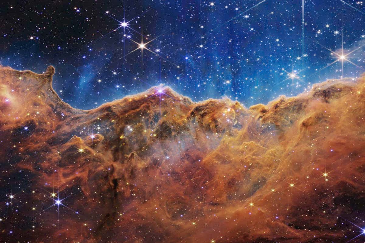 What looks much like craggy mountains on a moonlit evening is actually the edge of a nearby, young, star-forming region NGC 3324 in the Carina Nebula. Captured in infrared light by the Near-Infrared Camera (NIRCam) on NASA???s James Webb Space Telescope, this image reveals previously obscured areas of star birth. Called the Cosmic Cliffs, the region is actually the edge of a gigantic, gaseous cavity within NGC 3324, roughly 7,600 light-years away. The cavernous area has been carved from the nebula by the intense ultraviolet radiation and stellar winds from extremely massive, hot, young stars located in the center of the bubble, above the area shown in this image. The high-energy radiation from these stars is sculpting the nebula???s wall by slowly eroding it away. NIRCam ??? with its crisp resolution and unparalleled sensitivity ??? unveils hundreds of previously hidden stars, and even numerous background galaxies. Several prominent features in this image are described below. ??? The ???steam??? that appears to rise from the celestial ???mountains??? is actually hot, ionized gas and hot dust streaming away from the nebula due to intense, ultraviolet radiation. ??? Dramatic pillars rise above the glowing wall of gas, resisting the blistering ultraviolet radiation from the young stars. ??? Bubbles and cavities are being blown by the intense radiation and stellar winds of newborn stars. ??? Protostellar jets and outflows, which appear in gold, shoot from dust-enshrouded, nascent stars. ??? A ???blow-out??? erupts at the top-center of the ridge, spewing gas and dust into the interstellar medium. ??? An unusual ???arch??? appears, looking like a bent-over cylinder. This period of very early star formation is difficult to capture because, for an individual star, it lasts only about 50,000 to 100,000 years ??? but Webb???s extreme sensitivity and exquisite spatial resolution have chronicled this rare event. Located roughly 7,600 light-years away, NGC 3324 was first cat